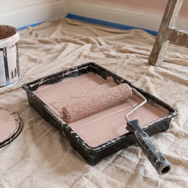Decorating detail: paint tray and roller beside a protected floor